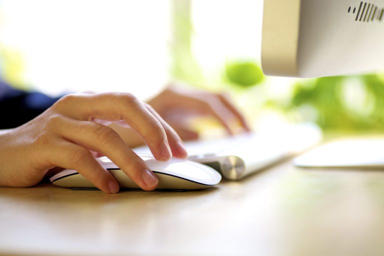Mains tapant sur un clavier et utilisant une souris, symbolisant le travail de gestion administrative.